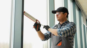 Asian worker sealing joints of office window video