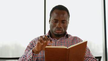 African American guy holding book, university student studying, learning language video