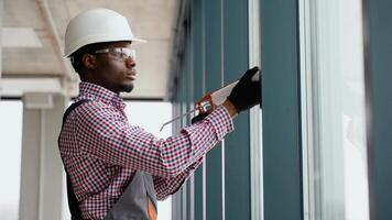 Black worker sealing joints of office window with silicone foam video