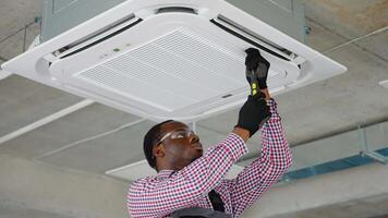 Black technician installing air conditioner in office. Air conditioner service indoors video