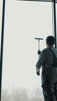 Asian male professional cleaning service worker cleans the windows and shop windows of a store with special equipment. Vertical video