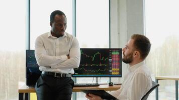 Two diverse traders making professional analysis while sitting in the office in front of multiple computer screens video