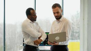 Due uomini commercianti broker con il computer portatile a ufficio insieme monitoraggio riserve dati candela grafici su schermo video
