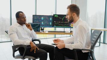 Team of stockbrokers are having a conversation in office with display screens. Analyzing data, graphs and reports for investment purposes. Creative teamwork traders video