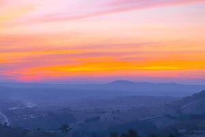 vistoso puesta de sol en el colinas hermosa paisaje con naranja cielo y nube antecedentes foto