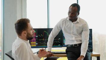 Two diverse traders making professional analysis while sitting in the office in front of multiple computer screens video