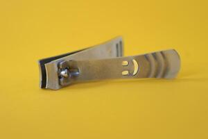 Stainless steel nail clippers isolated on yellow background photo