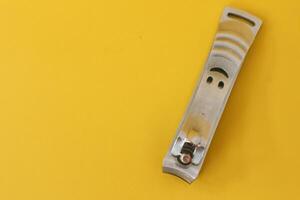 Stainless steel nail clippers isolated on yellow background photo