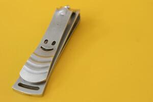 Stainless steel nail clippers isolated on yellow background photo