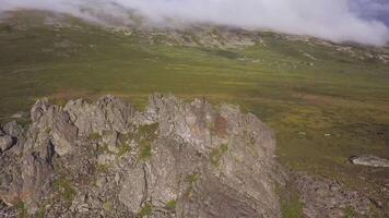 aérien vue sur vert Prairie avec solitaire Roche et nuageux ciel Contexte. incroyable montagnes paysage avec gros Roche à le milieu de le herbe. aérien coup de Montagne côté video