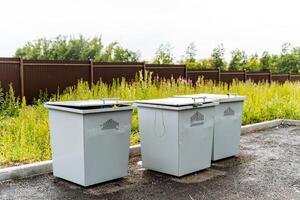 three dumpsters stand in the Parking lot in a private village, a container for collecting garbage photo