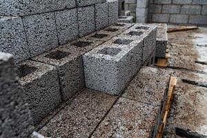 cinder blocks of gray concrete are neatly stacked in a pile, slender rows of bricks, material for building a house photo