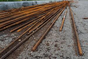 varilla para construcción es acostado en el asfalto, un pila de oxidado varillas, metal varillas naranja color foto