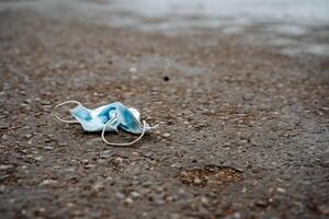 protective medical mask is lying like garbage on the asphalt, the used mask was crushed and thrown away, medical waste, photos on the topic of ecology