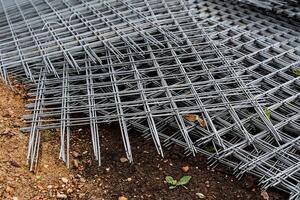hierro cuadrícula con cuadrado células para el construcción obras, un metal reja doblada en un pila foto