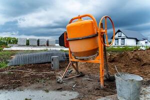 an orange concrete mixer where cement is prepared for construction works stands on the street photo