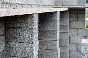 cinder blocks of gray concrete are neatly stacked in a pile, slender rows of bricks, material for building a house photo