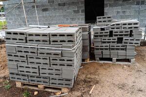 cinder blocks of gray concrete are neatly stacked in a pile, slender rows of bricks, material for building a house photo