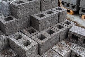 cinder blocks of gray concrete are neatly stacked in a pile, slender rows of bricks, material for building a house photo