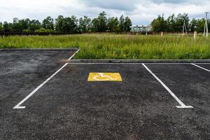 un amarillo firmar en el asfalto muestra un estacionamiento sitio para personas con discapacidades, para el desactivado, un la carretera firmar, marcas en el la carretera foto