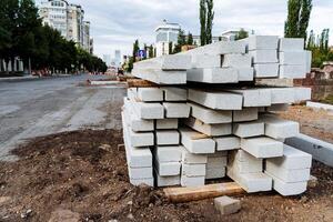 blanco hormigón bloques para pavimentación losas son apilado en el calle, un bordillo para un peatonal camino foto