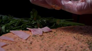 Hands preparing a pizza. Frame. Cook in the kitchen putting the ingredients on the pizza. Pizza concept. Production and delivery of food. Closeup hand of chef baker in white uniform making pizza at video