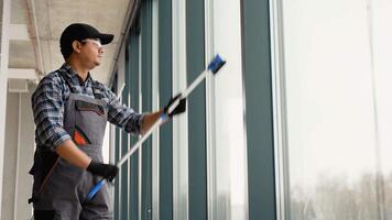 Asian male professional cleaning service worker cleans the windows and shop windows of a store with special equipment video