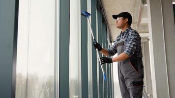 Indian man professional cleaning service worker in overalls cleans the pvc windows in office video