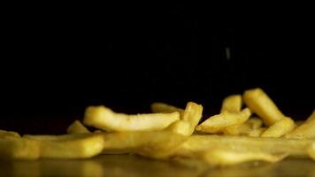 Französisch Fritten fallen auf das Tabelle isoliert auf schwarz Hintergrund. Fastfood. Französisch Fritten. fliegend gebraten Kartoffeln auf schwarz Hintergrund video