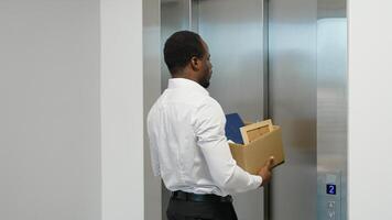Dismissed black worker with dismissal box entering into the modern elevator video