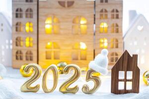 Golden figures number 2025 and tiny home on background of cozy windows of a house with warm light with festive decor of stars,snow and garlands. Greeting card, Happy New Year, cozy home photo