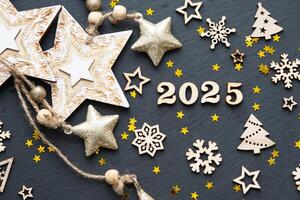 Happy New Year-wooden letters and the numbers 2025 on festive black background with sequins, stars, snow. Greetings, postcard. Calendar, cover photo