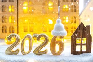 Golden figures number 2026 and tiny home on background of cozy windows of a house with warm light with festive decor of stars,snow and garlands. Greeting card, Happy New Year, cozy home photo