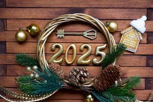 New Year House key with keychain cottage on festive brown wooden background with number 2025 in wreath, lights of garlands. Purchase, construction, relocation, mortgage, insurance photo