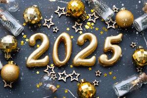 el dorado cifras 2025 hecho de velas en un negro Roca pizarra antecedentes son decorado con un festivo decoración de estrellas, lentejuelas, abeto sucursales, pelotas y guirnaldas saludo tarjeta, contento nuevo año. foto