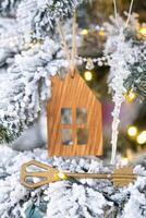 llave y minúsculo casa llavero en mano en antecedentes hada luces Navidad árbol. regalo para nuevo año, Navidad. edificio, diseño, proyecto, Moviente, seguro, hipoteca, alquilar y compra real bienes. foto