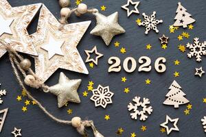 Happy New Year-wooden letters and the numbers 2026 on festive black background with sequins, stars, snow. Greetings, postcard. Calendar, cover photo