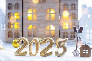 Golden figures number 2025, key and tiny home on background of cozy windows of a house with warm light with festive decor of stars,snow and garlands. Greeting card, Happy New Year, cozy home photo