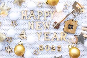 House key with keychain cottage on festive background with stars, lights of garlands. New Year 2025 wooden letters, greeting card. Purchase, construction, relocation, mortgage, insurance photo