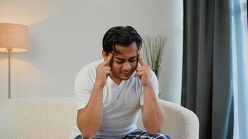 indio asiático hombre teniendo un dolor de cabeza a hogar en sofá video