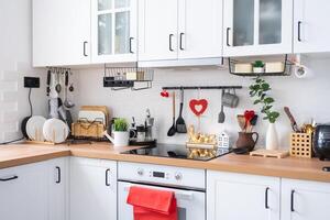 The interior of the kitchen in the house is decorated with red hearts for Valentine's Day. Decor on the table, stove, utensils, festive mood in a family nest photo