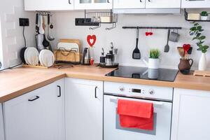 The interior of the kitchen in the house is decorated with red hearts for Valentine's Day. Decor on the table, stove, utensils, festive mood in a family nest photo