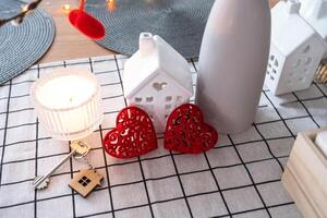 Key to tiny house of cozy home with Valentine decor on table of kitchen. Gift for valentines day, family love nest. design, project, moving to new house, mortgage, rent and purchase real estate photo