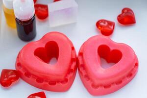 Handmade homemade soap in the shape of hearts for a Valentine's Day gift to your beloved. Perfumes and dyes, soap base on the table photo