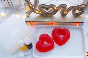 Handmade homemade soap in the shape of hearts for a Valentine's Day gift to your beloved. Perfumes and dyes, soap base on the table photo