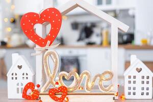 Key to tiny house of cozy home with Valentine decor on table of kitchen. Gift for valentines day, family love nest. design, project, moving to new house, mortgage, rent and purchase real estate photo