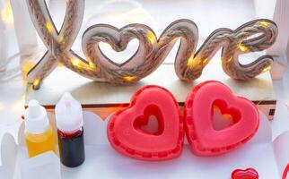 Handmade homemade soap in the shape of hearts for a Valentine's Day gift to your beloved. Perfumes and dyes, soap base on the table photo