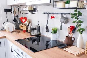 el interior de la cocina de la casa está decorado con corazones rojos para el día de san valentín. decoración en la mesa, estufa, utensilios, ambiente festivo en un nido familiar foto