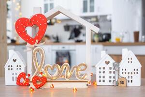 Key to tiny house of cozy home with Valentine decor on table of kitchen. Gift for valentines day, family love nest. design, project, moving to new house, mortgage, rent and purchase real estate photo