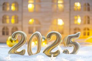 Golden figures number 2025 against the background of cozy windows of a house with warm light with festive decor of stars,snow and garlands. Greeting card, Happy New Year, cozy home photo